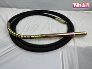 Coiled black hose with metal vibrator head and metal coupling on a white sheet.