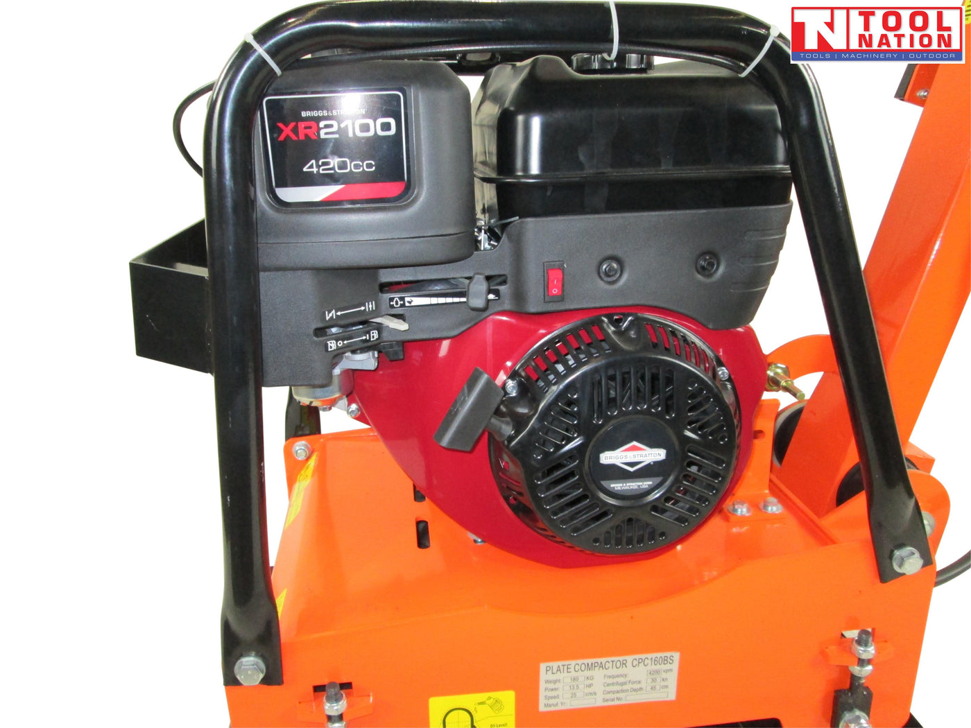 Close-up of a petrol engine mounted on an orange plate compactor with protective frame and warning labels.