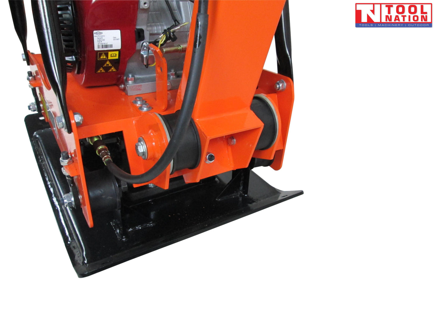 Close-up of an orange plate compactor base showing the handle hinge, black base plate, hose, bolts, and engine section.