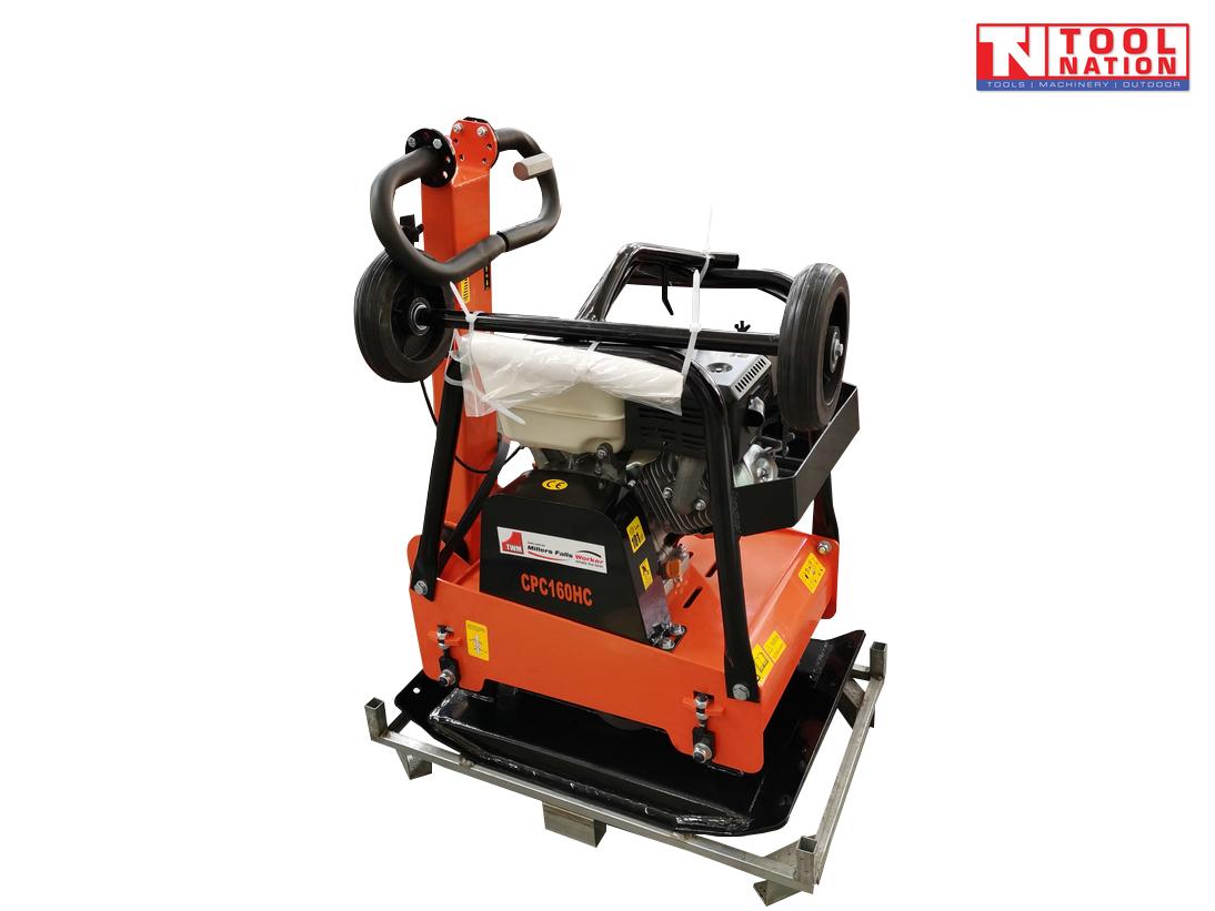 Orange plate compactor on a metal frame with petrol engine, protective cage, handle, wheels, black base plate, and logo in the top corner.
