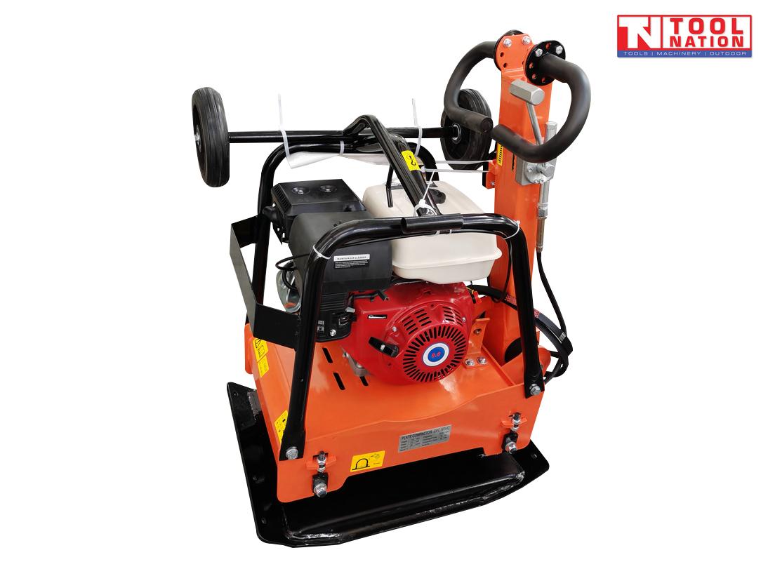 Rear angled view of an orange plate compactor with petrol engine, protective frame, handle, wheel kit, black base plate, and logo in the top corner.
