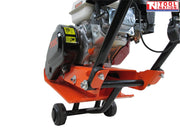 Close-up rear view of an orange plate compactor showing the petrol engine, black belt cover, handle frame, wheels, and logo in the top corner.