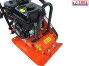 Close-up angled view of an orange plate compactor showing the petrol engine, protective frame, base plate, belt cover, and warning labels.