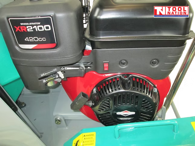 Close-up of a petrol engine on a floor saw showing the pull start, fuel tank, control lever, and surrounding frame.