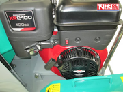 Close-up of a petrol engine on a floor saw showing the pull start, fuel tank, control lever, and surrounding frame.