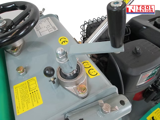 Close-up of a floor saw height adjustment area showing the hand wheel, vertical lever, labels, bolts, and engine section.