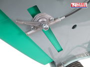 Close-up of a floor saw control lever beside a teal panel, clear hose, and grey frame.