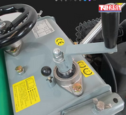 Close-up of a floor saw top section showing a black hand wheel, grey frame, lever, bolts, labels, and handle rail.