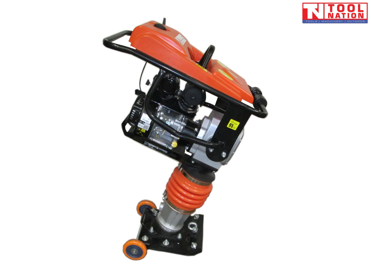 Angled view of an orange tamping rammer with petrol engine, black frame, orange bellows, black base plate, wheels, and logo in the top corner.