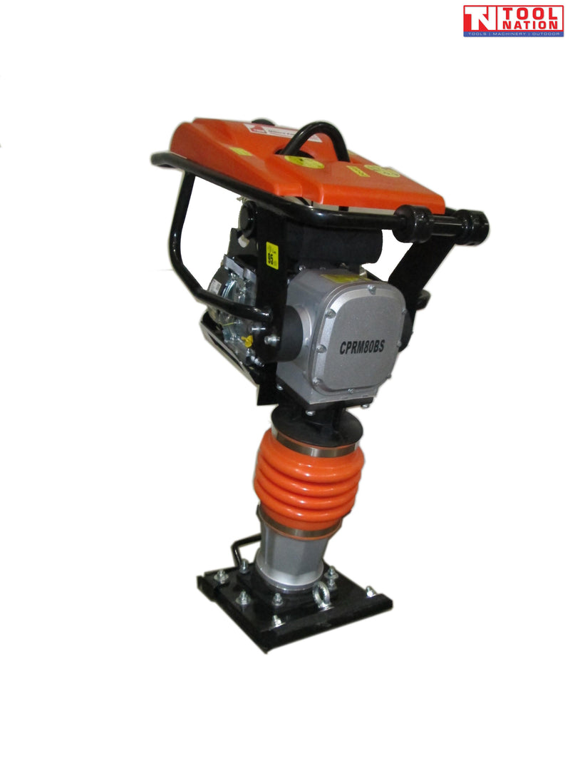 Orange tamping rammer with petrol engine, black frame, orange bellows, black base plate, warning labels, and logo in the top corner.