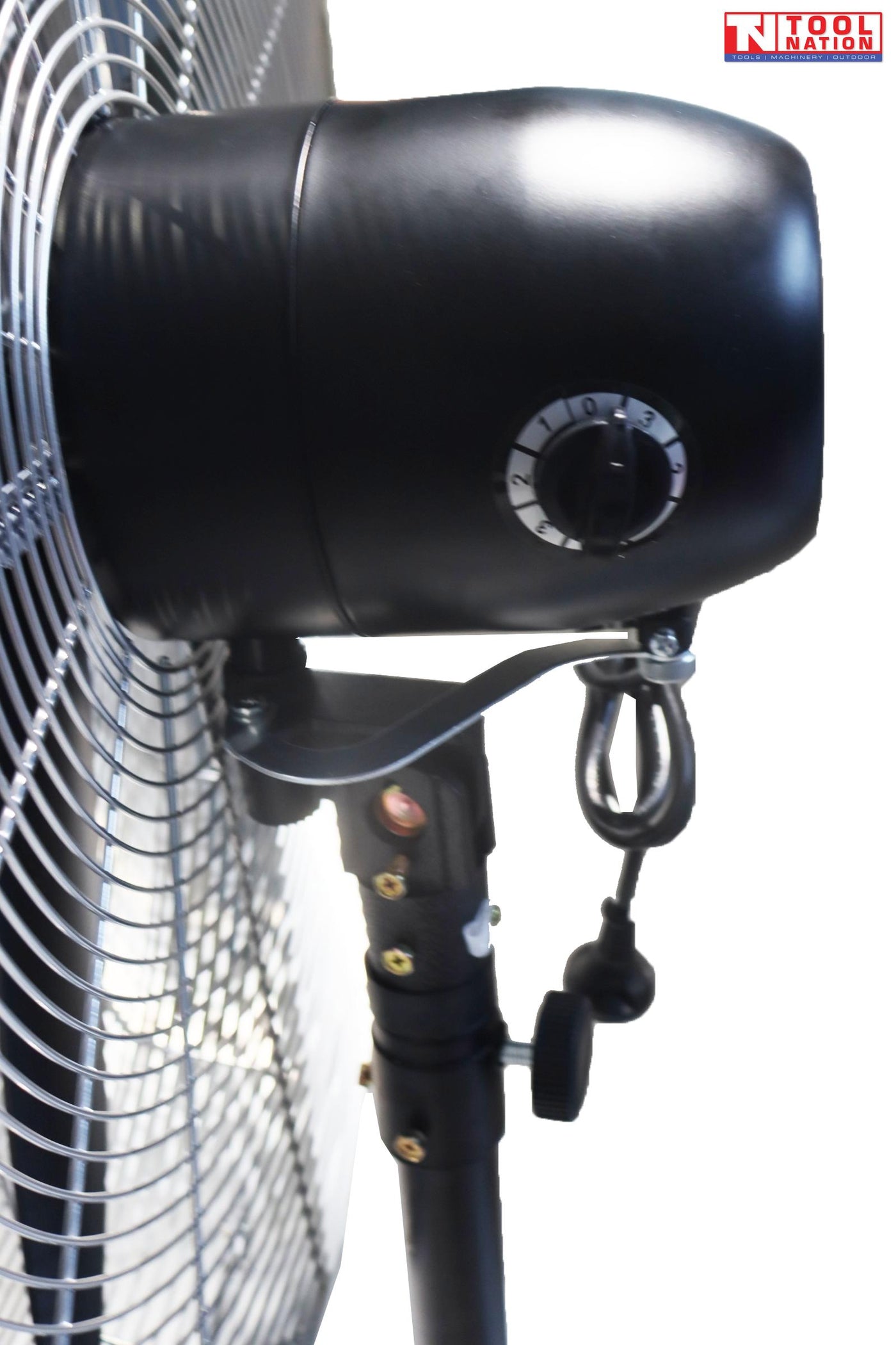 Angled view of a large pedestal fan showing round grille, three blades, adjustable stand, and cross base.