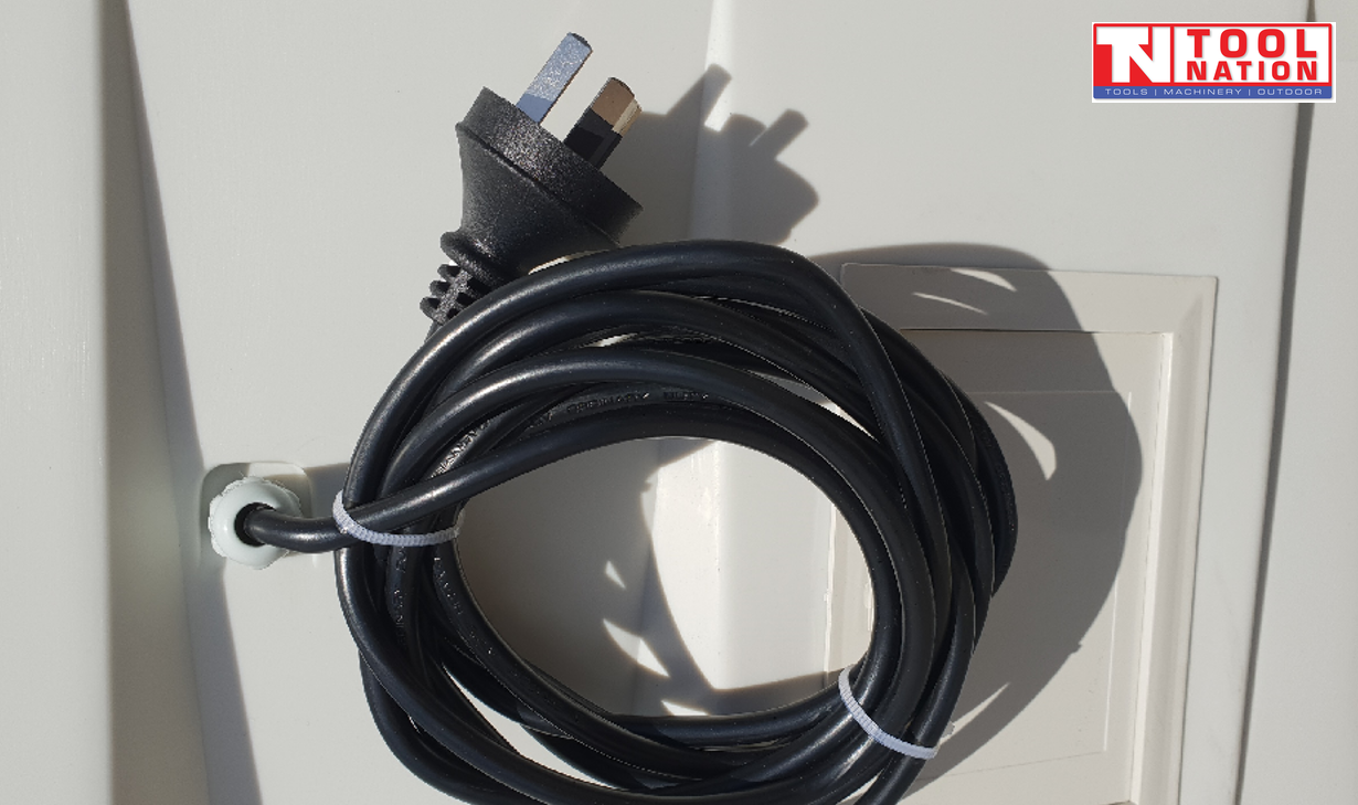 Close-up of a coiled black power cord and three-pin plug on the side panel.