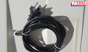 Close-up of a coiled black power cord and three-pin plug on the side panel.