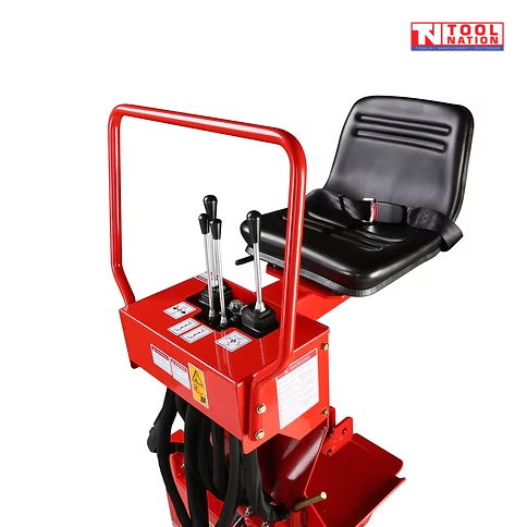 Close-up of a red backhoe control station showing black seat, control levers, safety rail, hydraulic hoses, labels, and logo in the top corner.