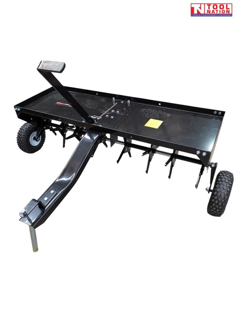 Black towable lawn aerator with a tray, drawbar, upright handle, two tyres and visible coring tines underneath.