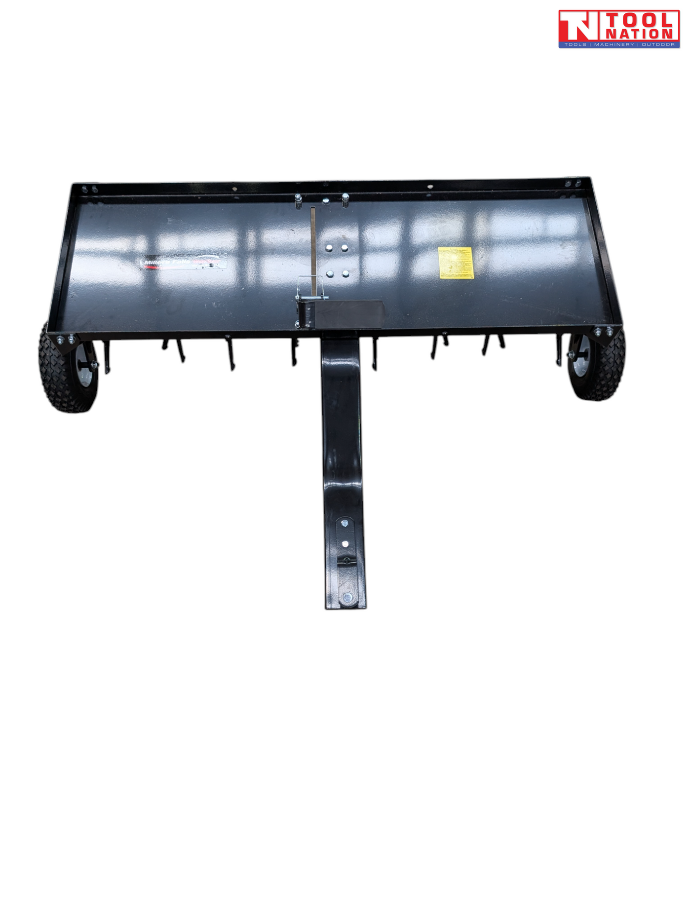 Front view of a black towable lawn aerator with a tray, drawbar, two tyres and visible coring tines underneath.