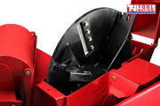 Close-up of a black internal chipper disc with visible bolts and blades beside red machine panels.