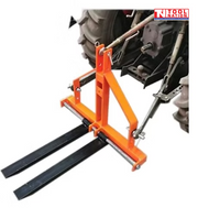 Orange forklift attachment connected behind a tractor, showing two black forks, linkage arms, and a logo in the top right corner.