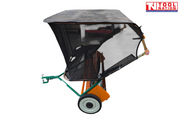 Side view of an orange and green towable lawn sweeper with a black mesh collection bag, drawbar and one visible tyre.