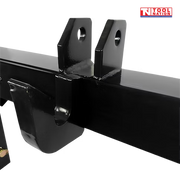 Close-up of the top hook bracket area on a black quick hitch attachment, with bolt holes and a logo in the top right corner.