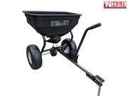 Black tow-behind spreader with an open hopper, long drawbar, upright handle, two treaded tyres, metal pin and Tool Nation logo.