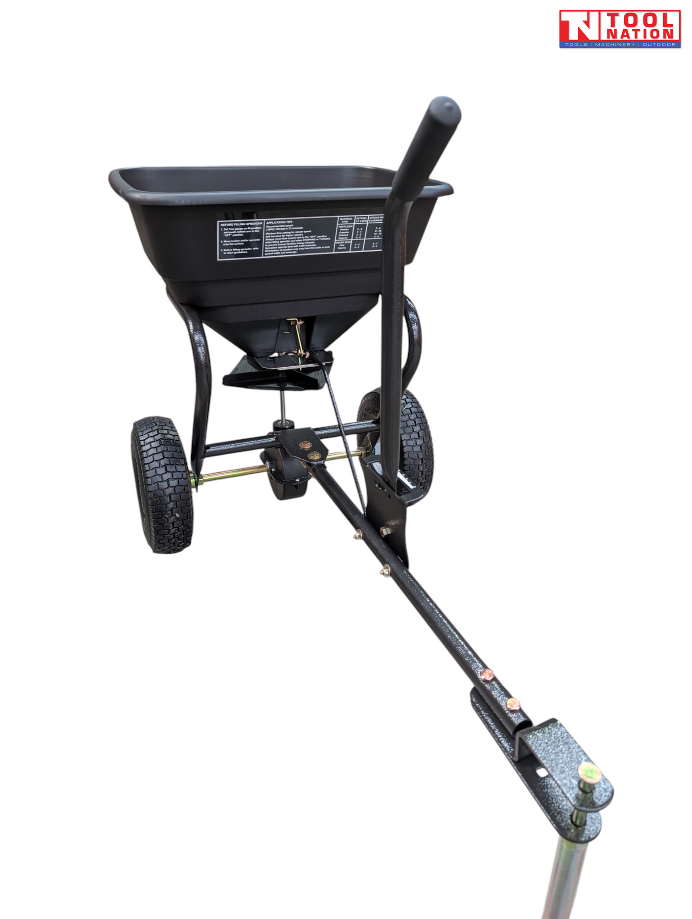 Black walk-behind spreader shown from the front side with an open hopper, long handle, two treaded tyres and Tool Nation logo.