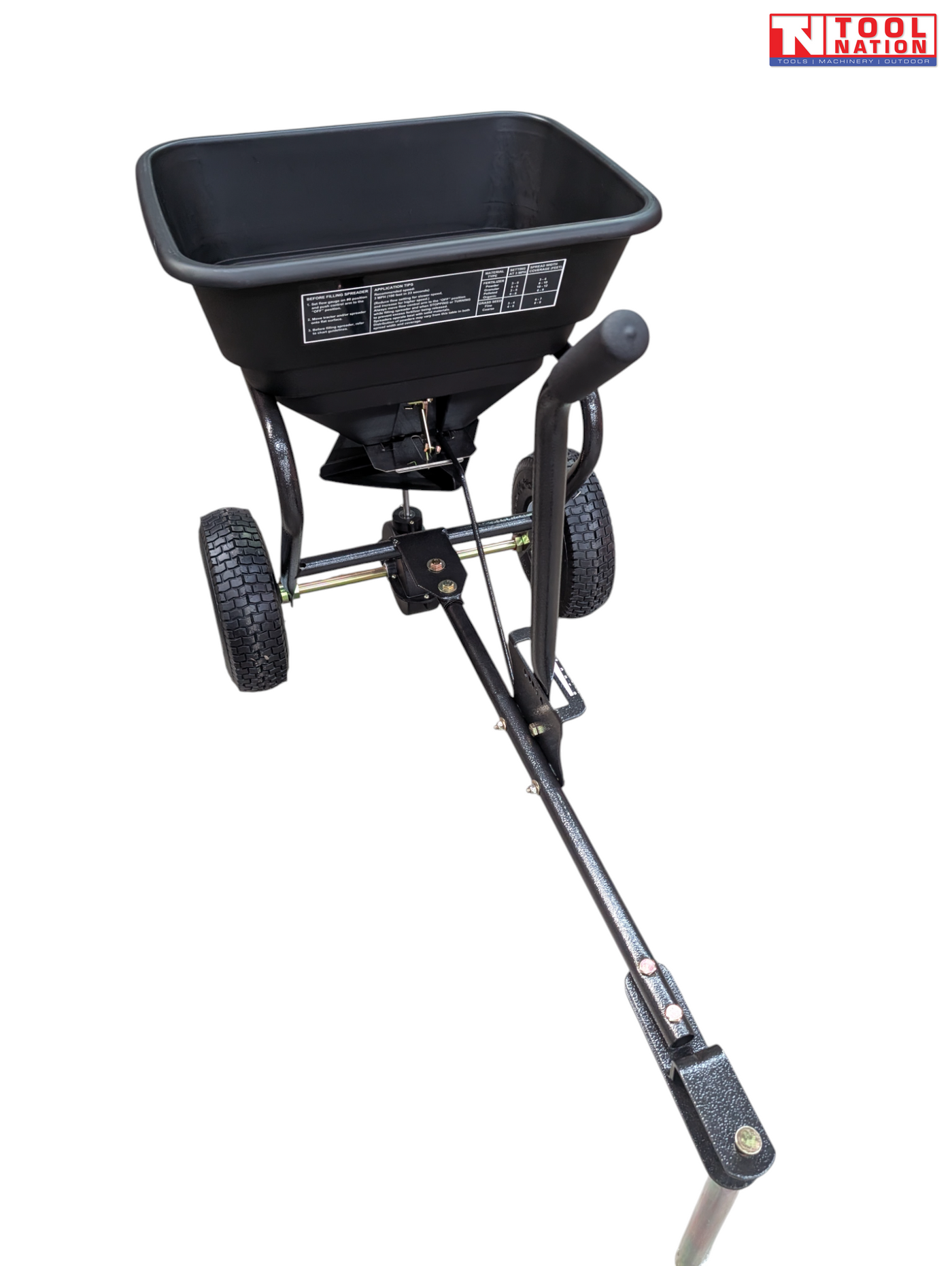 Black walk-behind spreader shown from above with an open hopper, long handle, two treaded tyres and Tool Nation logo.