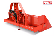 Rear angled view of a red bucket attachment with triangular mounting frame, black hydraulic hoses, pins, support leg, and raised side panels, with a logo in the top right corner.