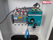 Inside view of an electrical cabinet showing terminal blocks, wired components, switch module, labels, and a logo in the top right corner.