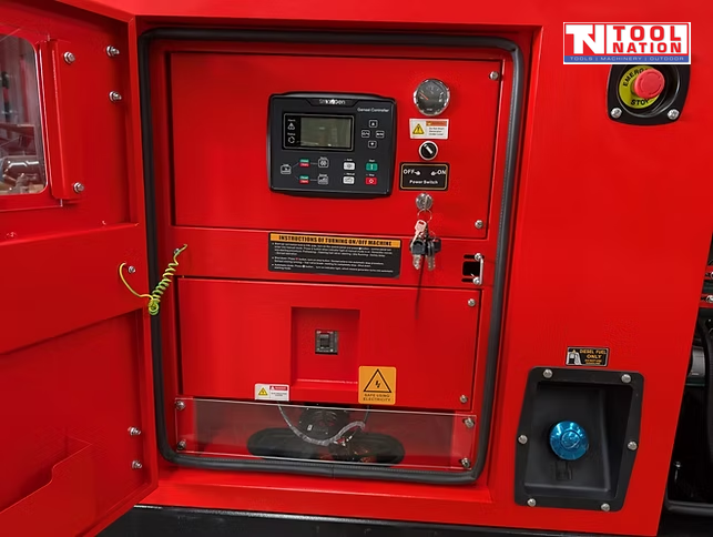 Close-up of the generator control panel inside an open access door, with switches, display screen, keys, and a blue outlet socket.