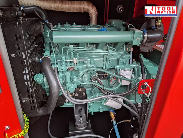 Internal view of the generator showing the engine and surrounding hoses, filters, and wiring inside the red enclosure.