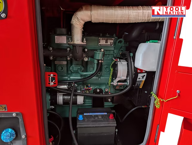 Internal view of the generator showing the engine, battery, coolant reservoir, and wiring inside the red enclosure.