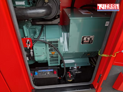 Internal view of the generator showing the alternator assembly, battery, wiring, and engine bay components inside the red cabinet.