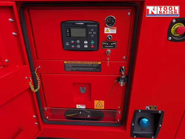 Close-up of the generator control panel with digital controller, gauges, key switch, emergency stop button, and covered outlet socket on the red cabinet.