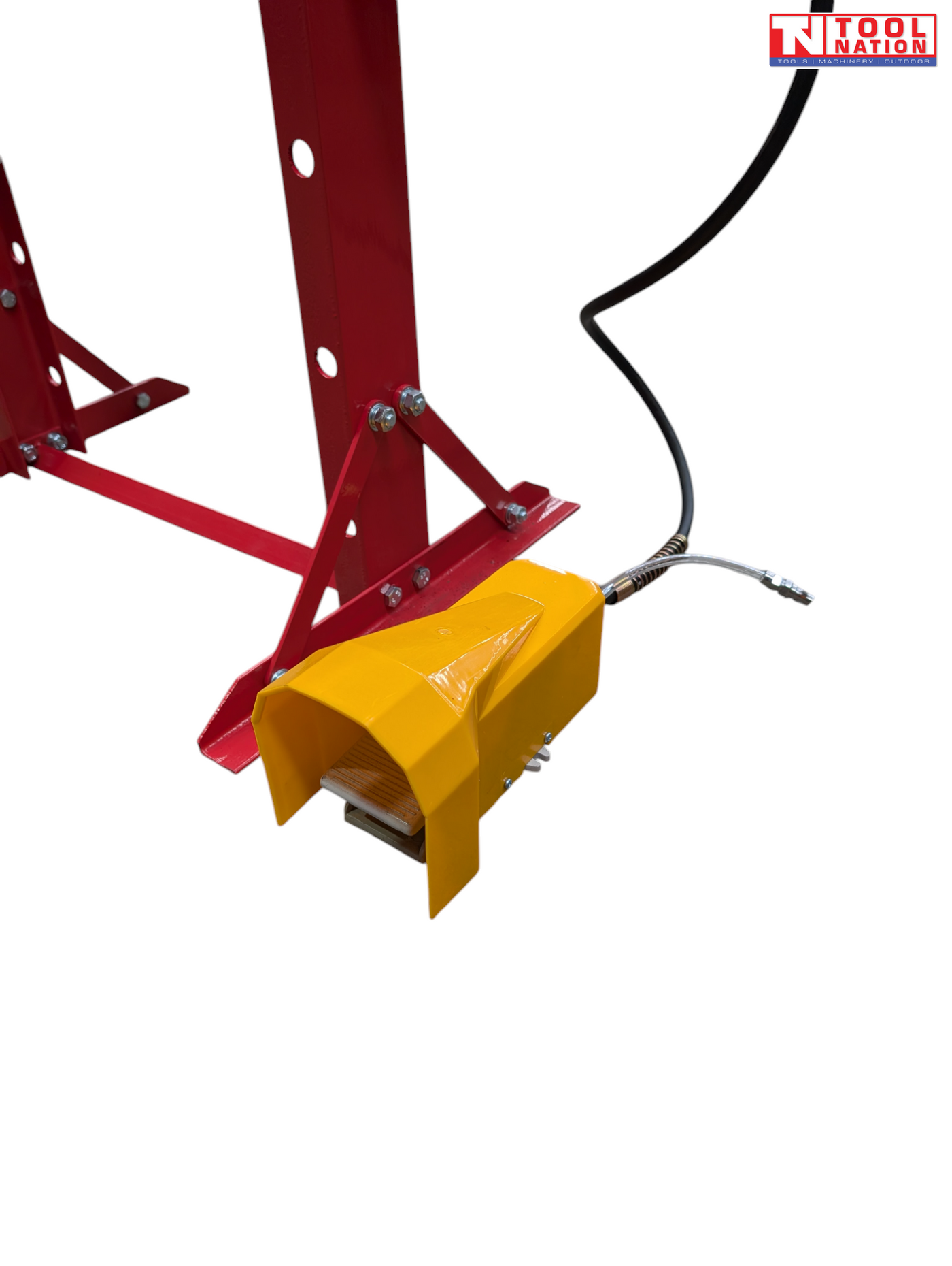 Close-up of a yellow foot pedal connected to the red frame and black hose of the shop press.