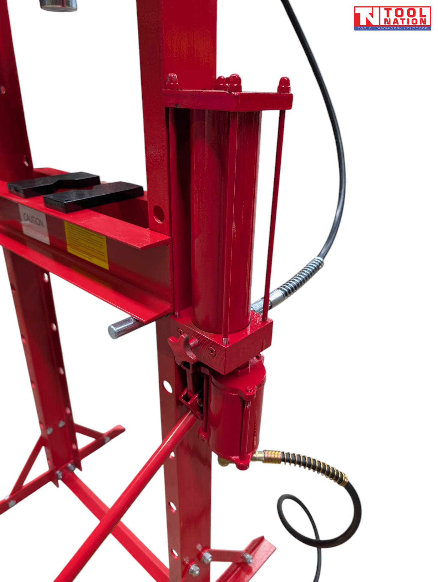 Close-up side view of the red hydraulic cylinder, pump assembly, black hose, and handle beside the press bed.