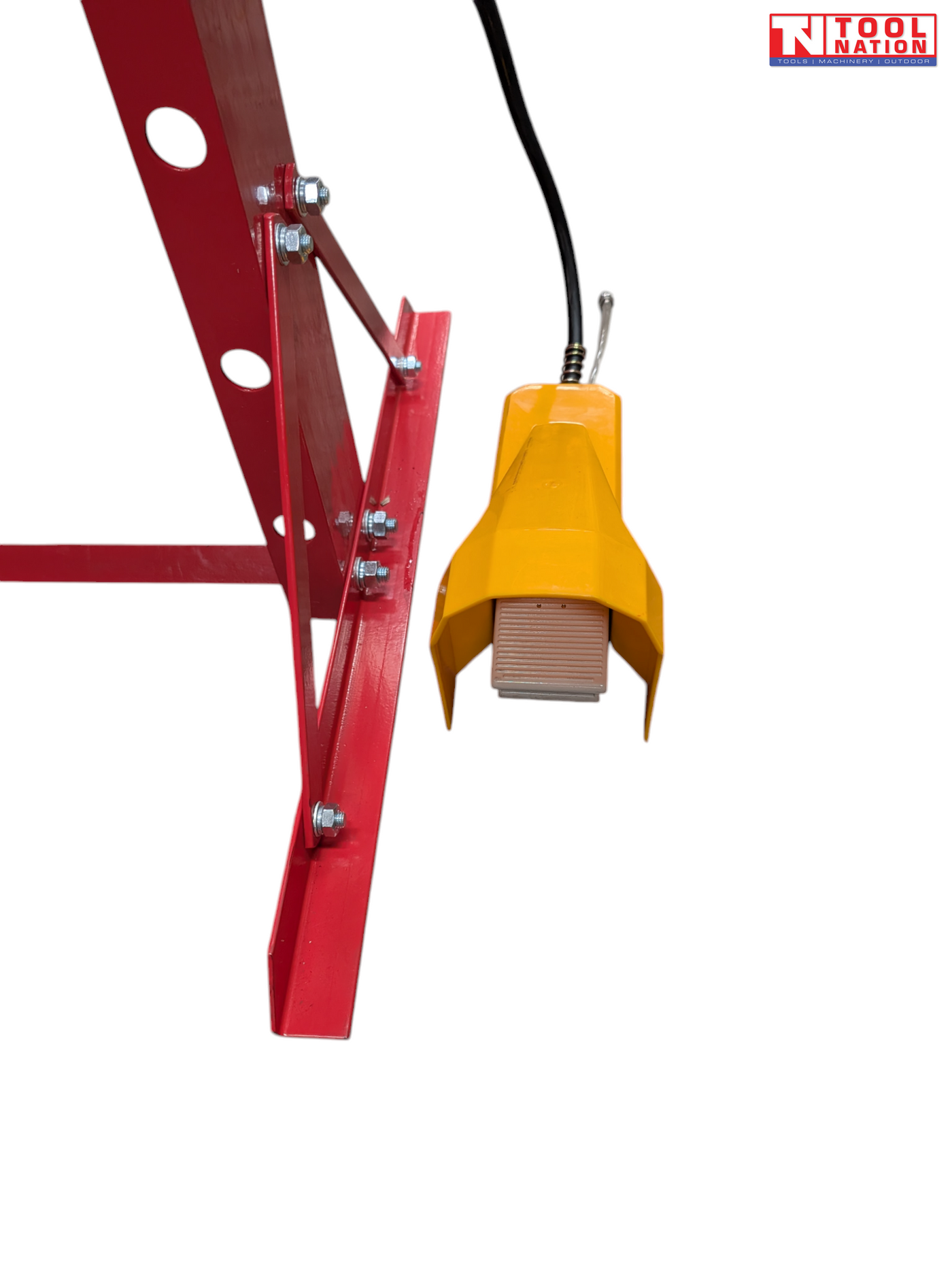 Close-up of a yellow foot pedal hanging beside the red frame of the shop press.