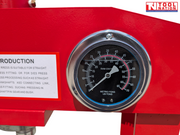 Close-up of a round pressure gauge mounted on the red upper frame of the shop press.