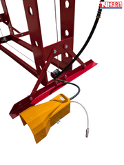Close-up of yellow foot pedal, black hose, silver air line, and red lower frame