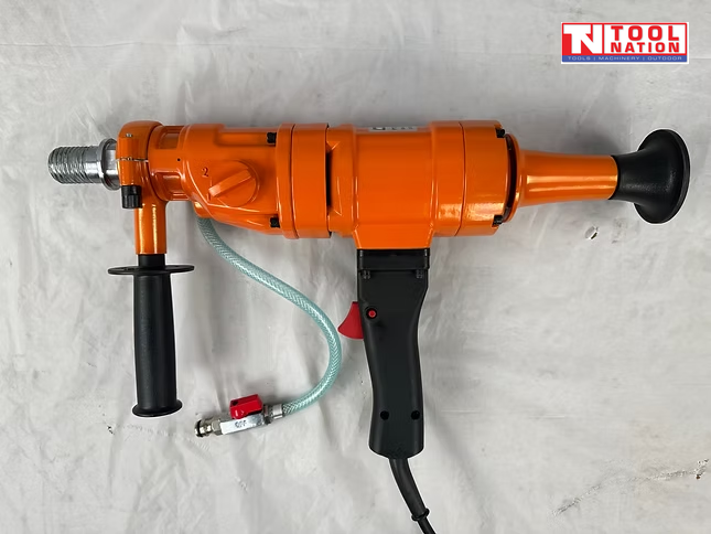 Orange handheld core drill with side handle, rear handle, water hose, power cord, and logo in the top corner.