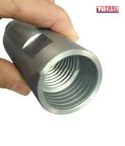 Close-up of a silver core drill adapter showing the internal threads and side opening held between fingers.