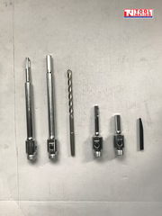 Metal drill adapters, drill bit, and drift tool laid out on a light background with logo in the top corner.