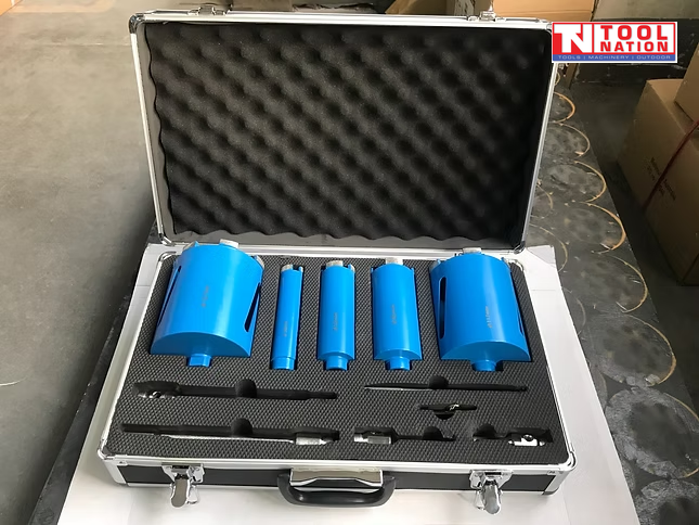 Open carry case containing blue core drill bits, metal adapters, drill bits, black foam insert, and logo in the top corner.