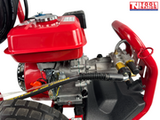 Close-up of a pressure washer fuel tank, engine, pump fittings, black hose, and red front frame.