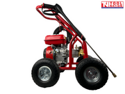 Side view of a red pressure washer with spray wand, engine, four wheels, and a logo in the top right corner.