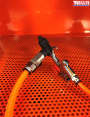 Close-up of spray gun with orange hose on perforated metal work surface