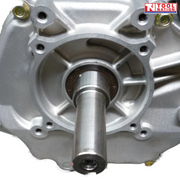 Close-up of a silver engine output shaft with surrounding bolt holes and engine housing.