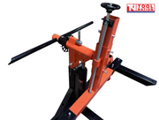 Close-up of an orange and black vehicle rotisserie upright with adjustment wheel, threaded rod, hydraulic jack, support arm, and logo in the top right corner.