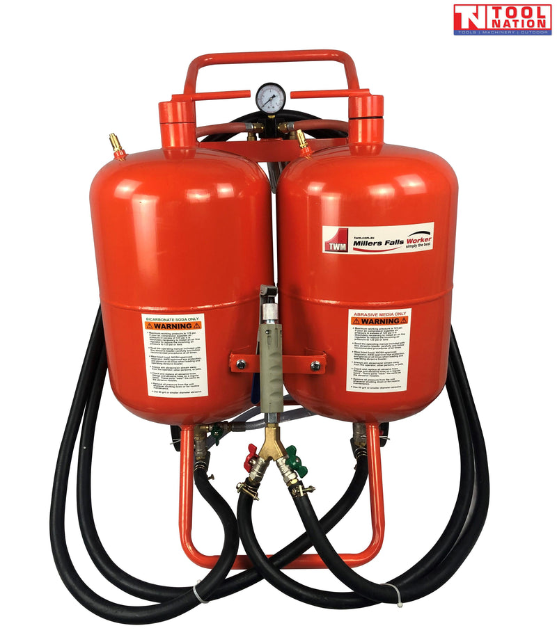 Front view of a twin-tank blasting unit on a wheeled frame, showing two red tanks, pressure gauge, central spray handle and coiled black hoses.