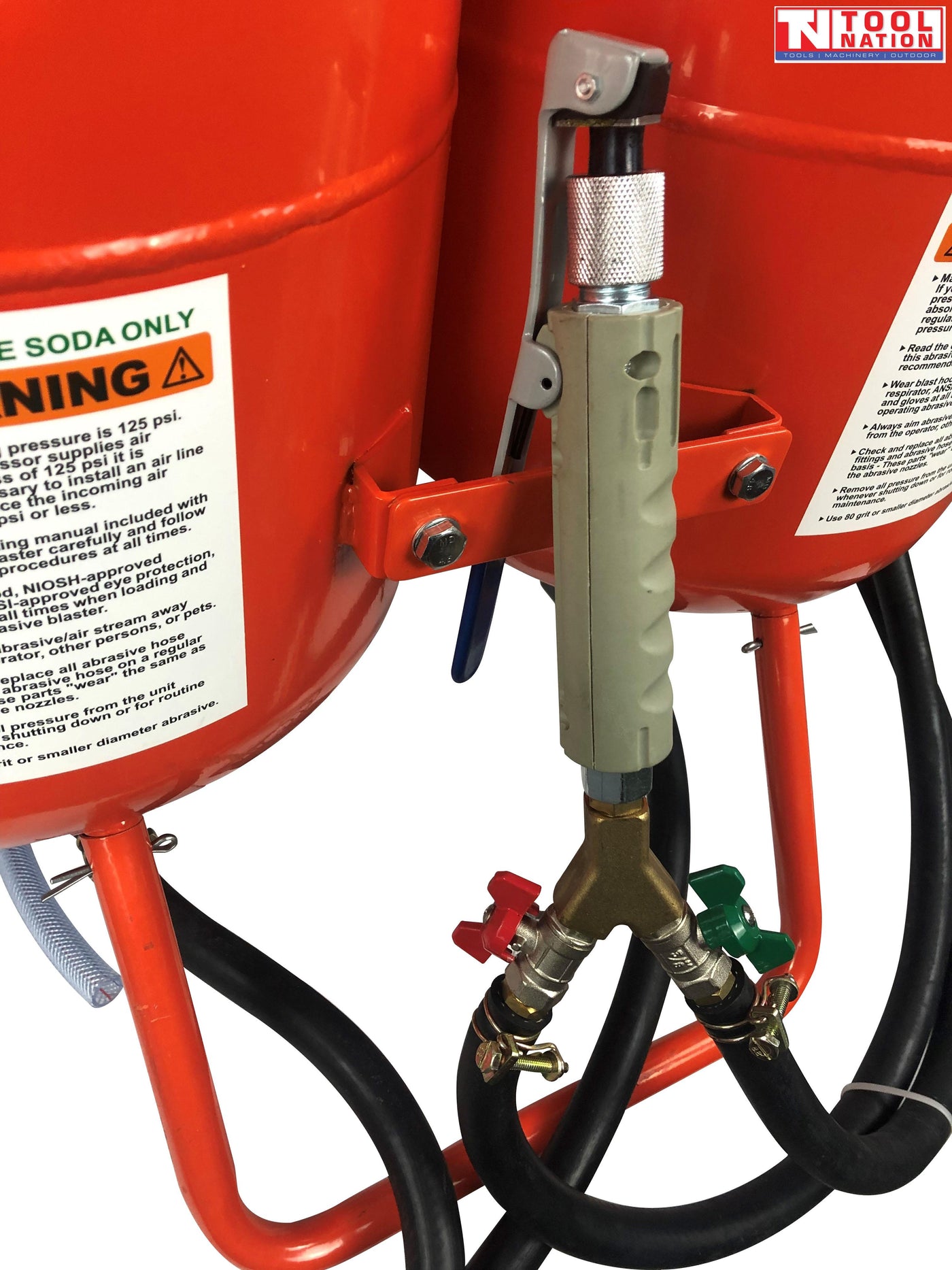Close-up of the blasting gun handle mounted between the two tanks, with red and green control valves and black hoses connected below.